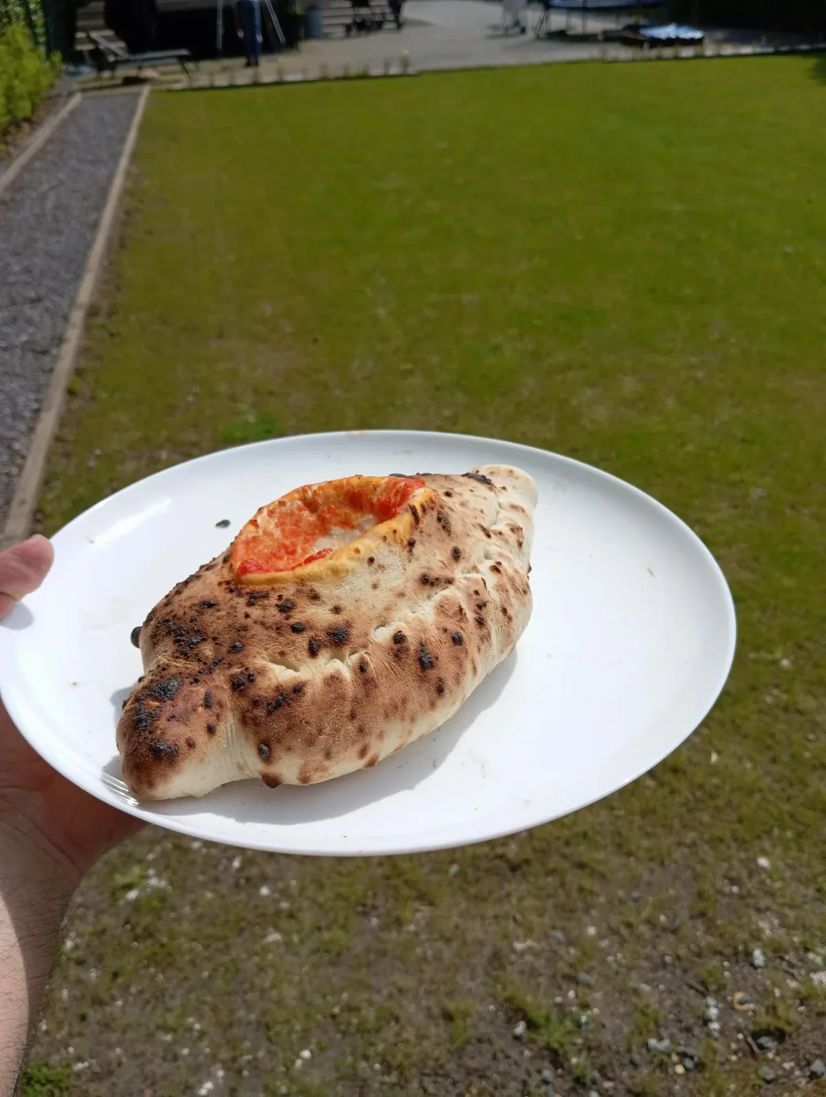 Een calzone op een bord, buiten op het gras