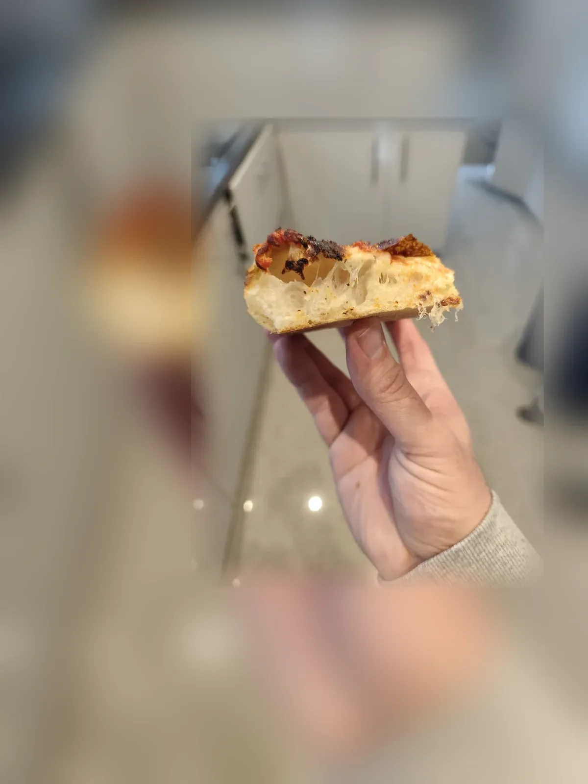 Een stuk pizza in de hand, met de luchtige korst