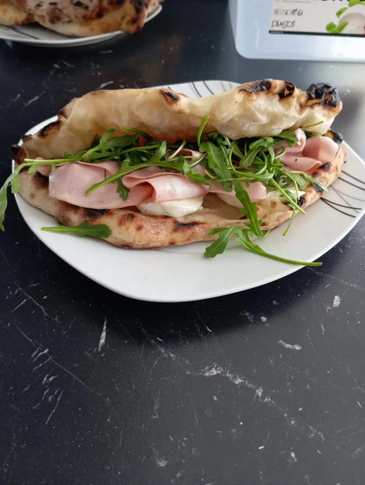 Een broodje van pizzadeeg met ham en rucola